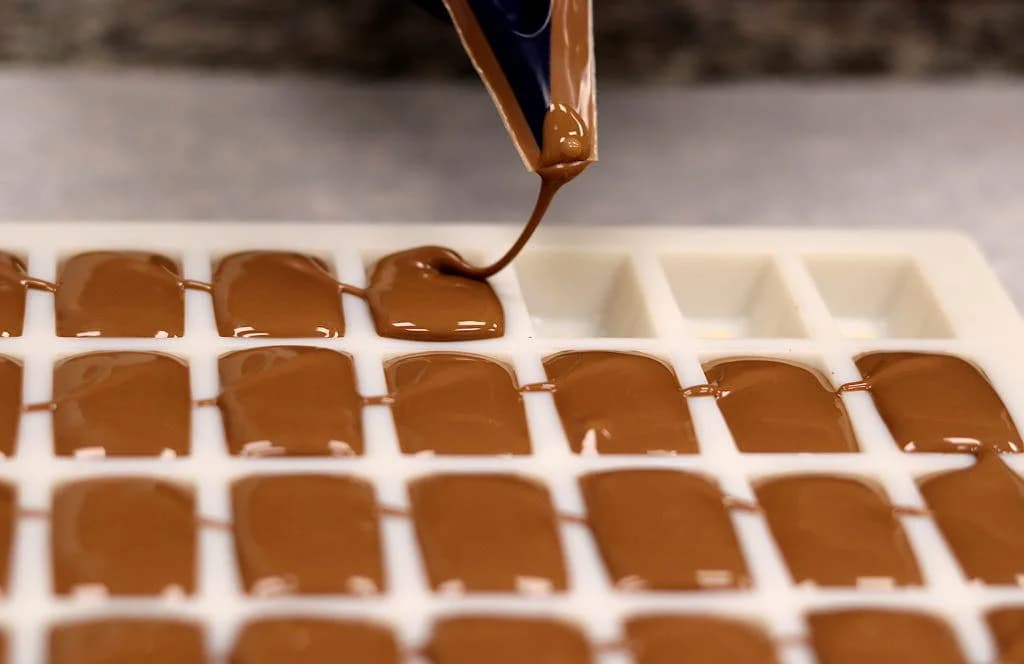 Pochage de chocolats à la main dans l'atelier Aux Délices Lorraines